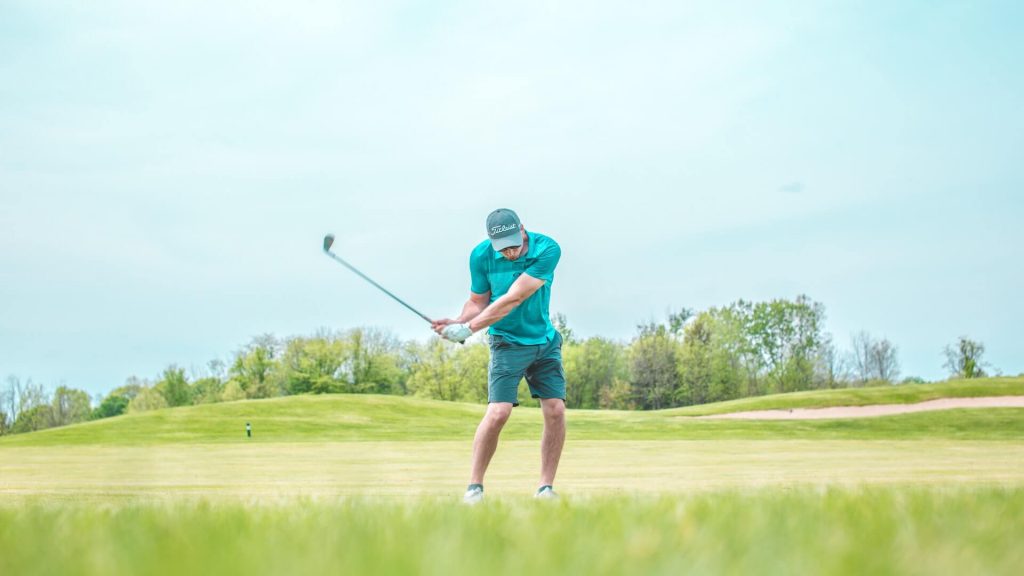 A man swinging at the golf ball on a course.