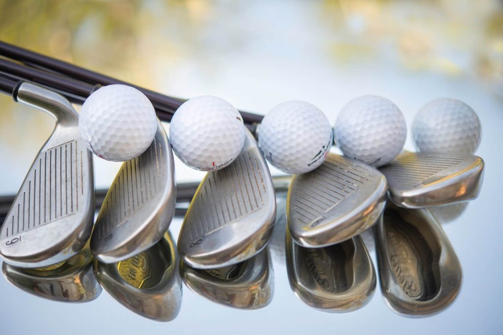 A row of golf clubs with balls on them.