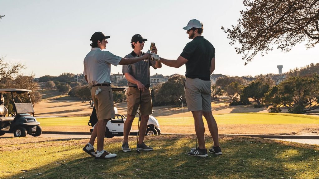 Three men shaking hands on a golf course.