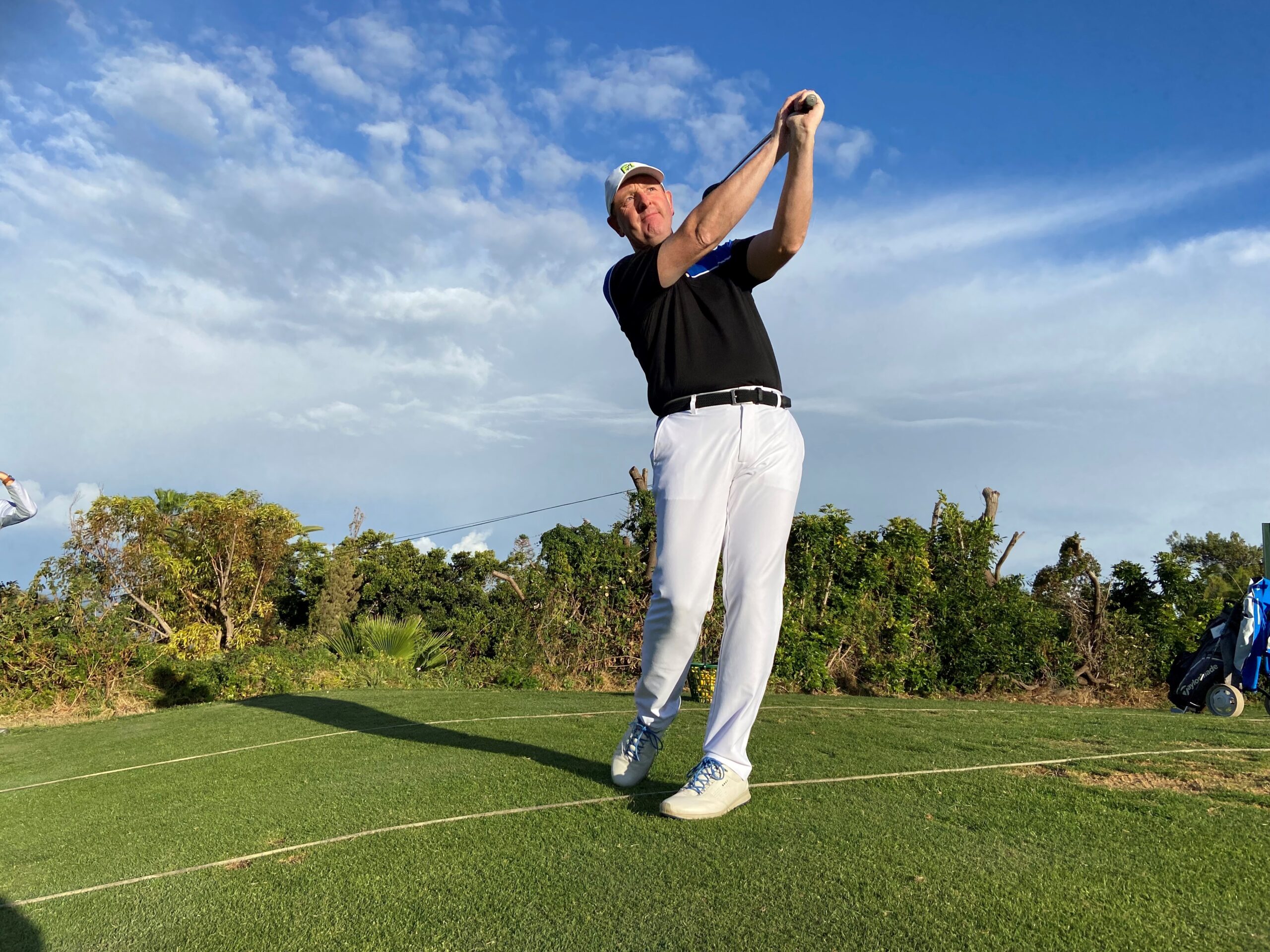 A man swinging at the ball on a golf course.