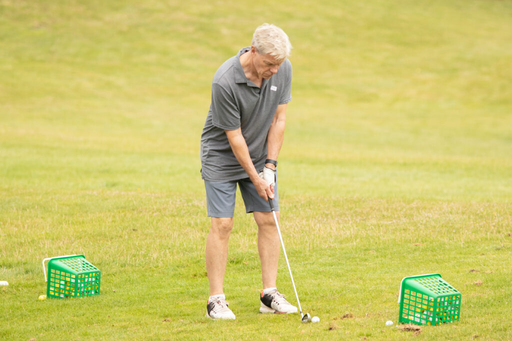 Man golfing on a green course.